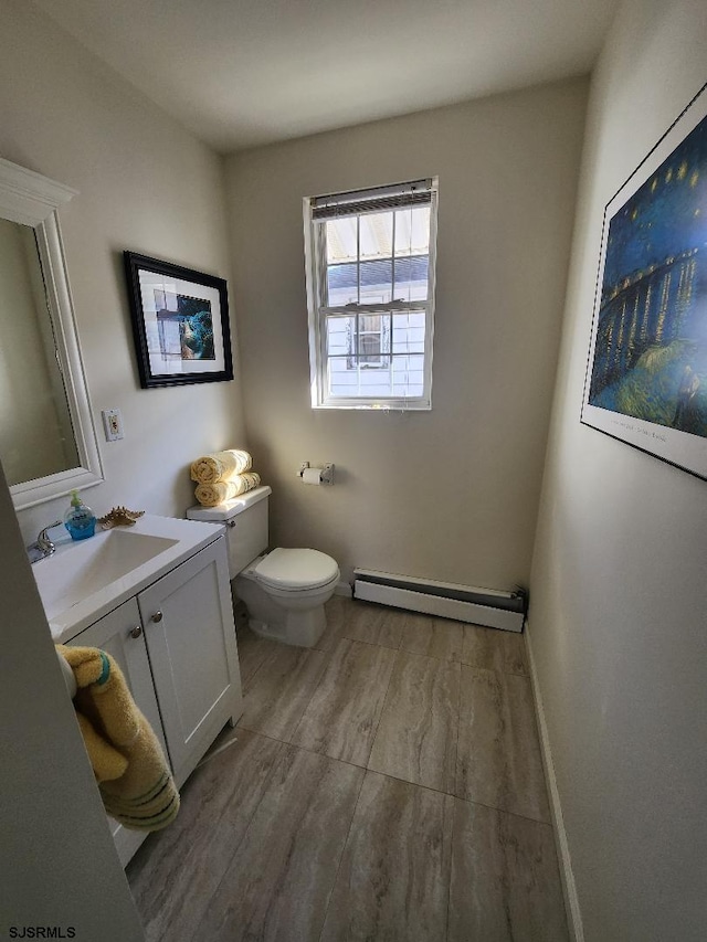 bathroom with hardwood / wood-style floors, a baseboard radiator, vanity, and toilet