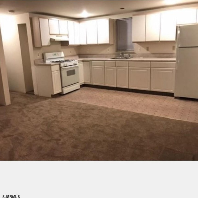 kitchen with white cabinets, white appliances, light colored carpet, and sink