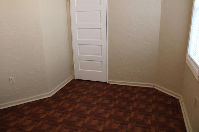 spare room featuring dark parquet flooring