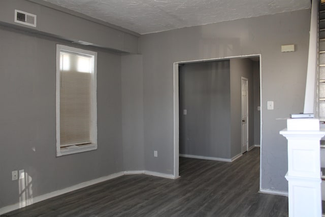 unfurnished room featuring a textured ceiling and dark hardwood / wood-style floors