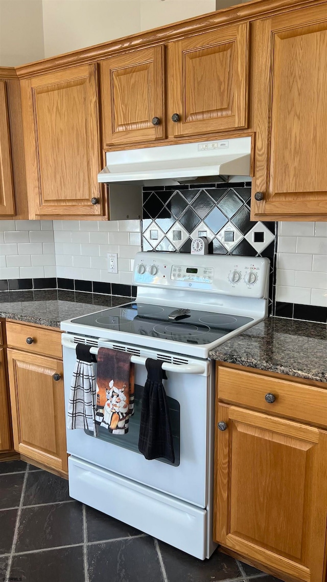 kitchen featuring dark tile patterned floors, dark stone counters, tasteful backsplash, and electric stove