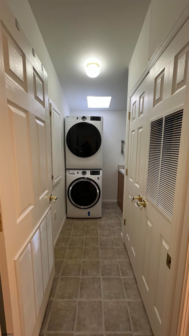 washroom featuring dark tile patterned floors and stacked washer and clothes dryer