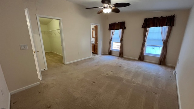 unfurnished bedroom featuring a spacious closet, ceiling fan, light colored carpet, and a closet