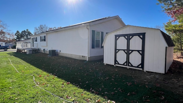 view of property exterior featuring central AC unit, a wooden deck, a yard, and a storage shed