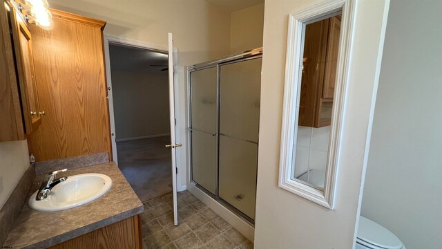 bathroom featuring vanity, toilet, and a shower with door