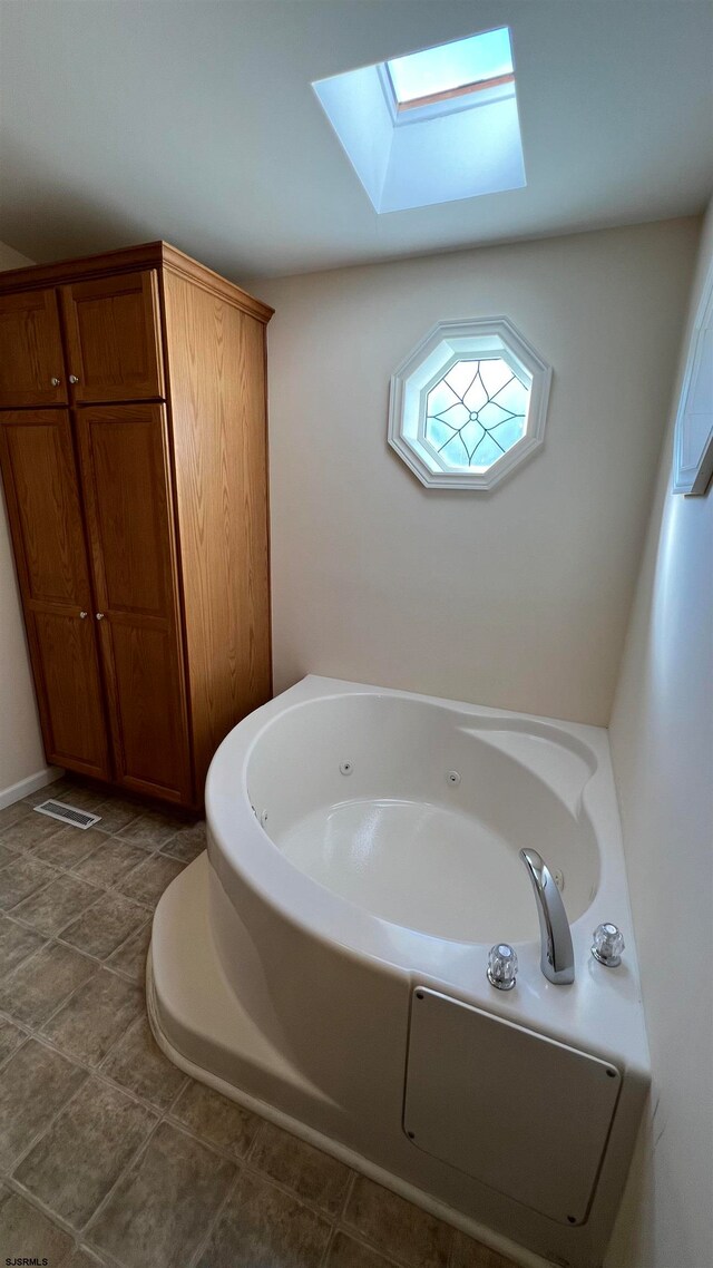 bathroom with a bathtub, a skylight, and tile patterned flooring