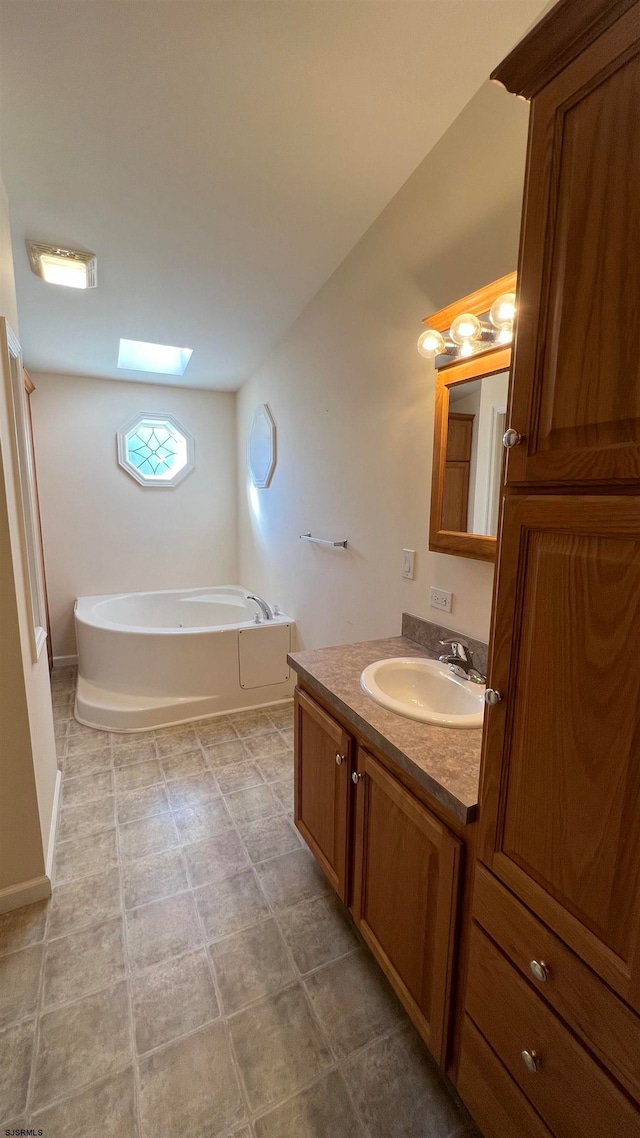 bathroom featuring a bathtub, vanity, a skylight, and tile patterned flooring