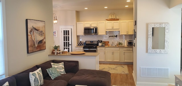 kitchen featuring sink, appliances with stainless steel finishes, backsplash, light hardwood / wood-style flooring, and white cabinets