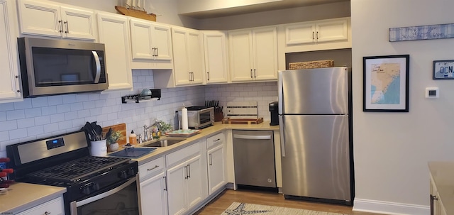 kitchen with white cabinetry, appliances with stainless steel finishes, decorative backsplash, and light hardwood / wood-style flooring