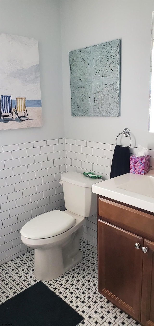 bathroom with vanity, tile patterned floors, toilet, and tile walls