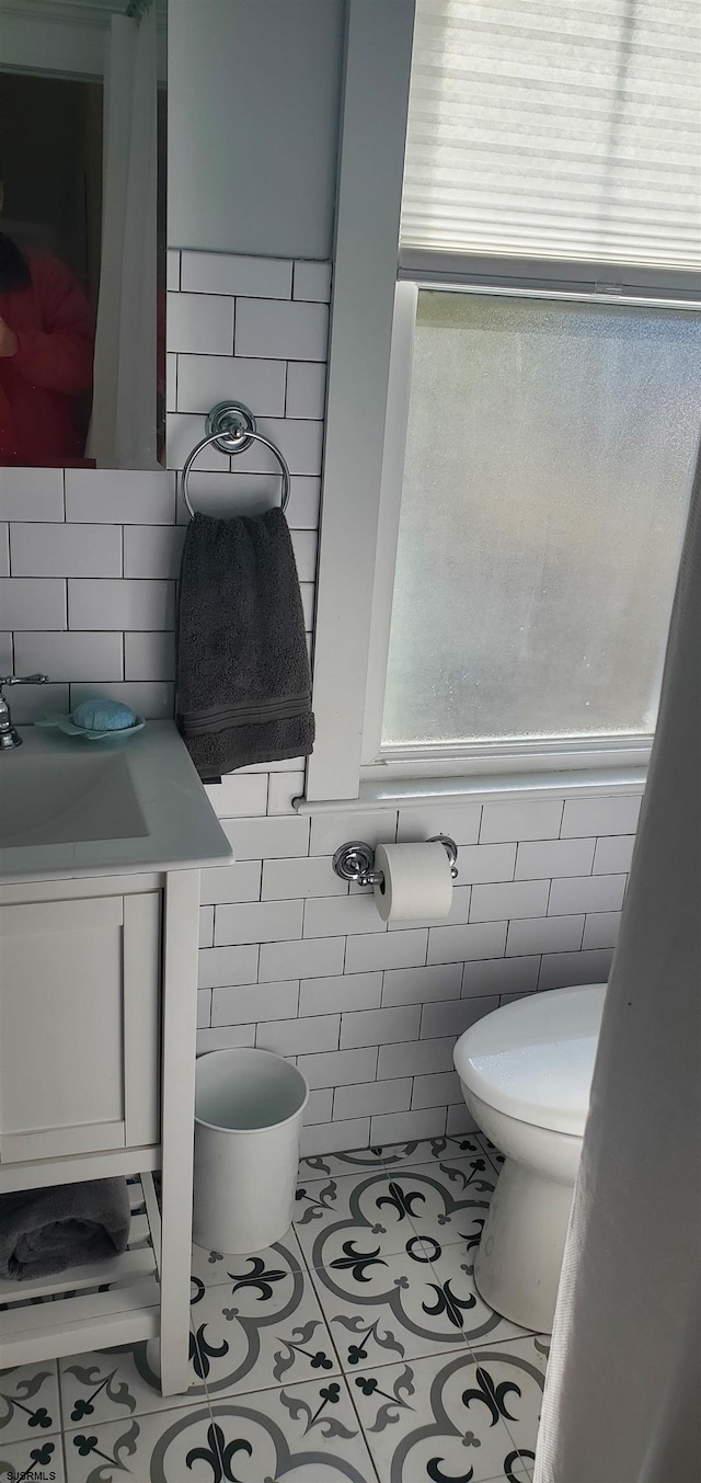 bathroom with tile walls, tile patterned flooring, vanity, and toilet