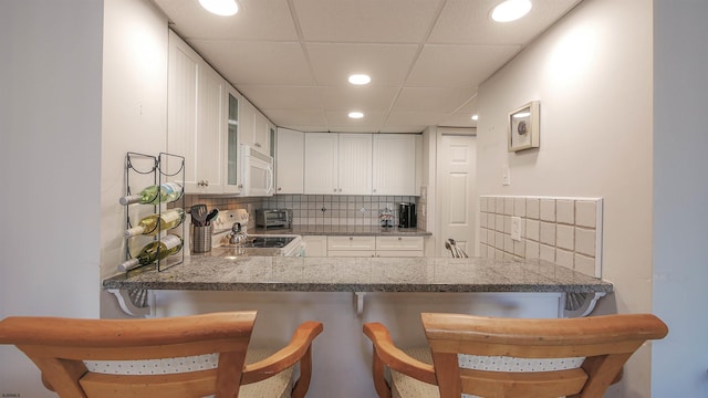 4540 W Brigantine Ave Unit N-102, Brigantine, NJ 08203 - kitchen with white microwave, electric stove, backsplash, white cabinets, and recessed lighting