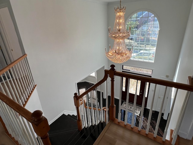 staircase with hardwood / wood-style floors and an inviting chandelier