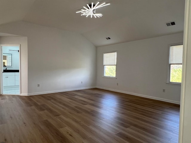 unfurnished room with dark hardwood / wood-style floors, vaulted ceiling, and a notable chandelier