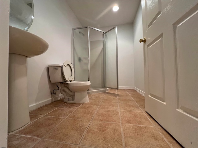 bathroom featuring tile patterned floors, toilet, and a shower with door