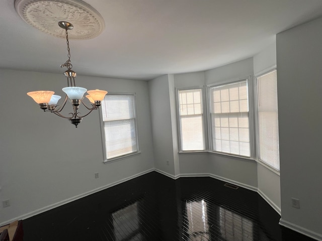 spare room with hardwood / wood-style floors and a notable chandelier