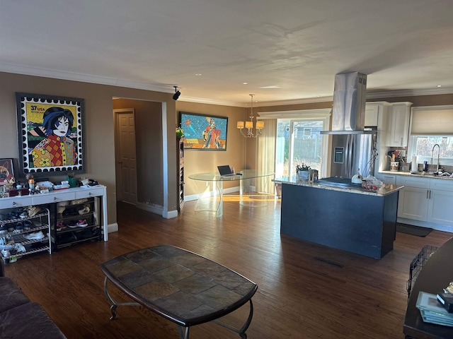 living room featuring dark hardwood / wood-style flooring, a notable chandelier, sink, and crown molding