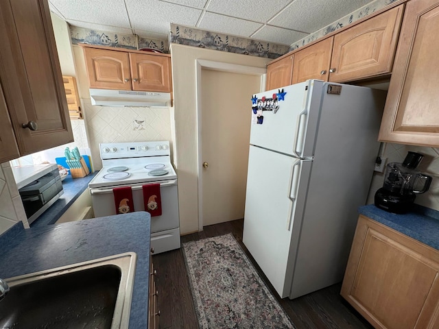 kitchen with a paneled ceiling, sink, white appliances, dark wood-type flooring, and decorative backsplash