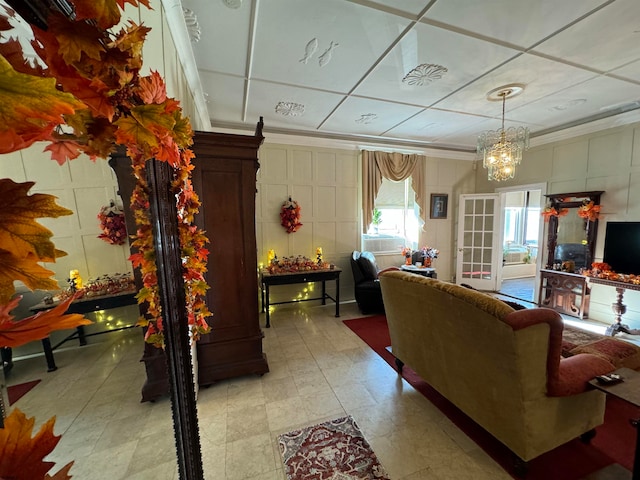 living room featuring a chandelier, crown molding, and a drop ceiling