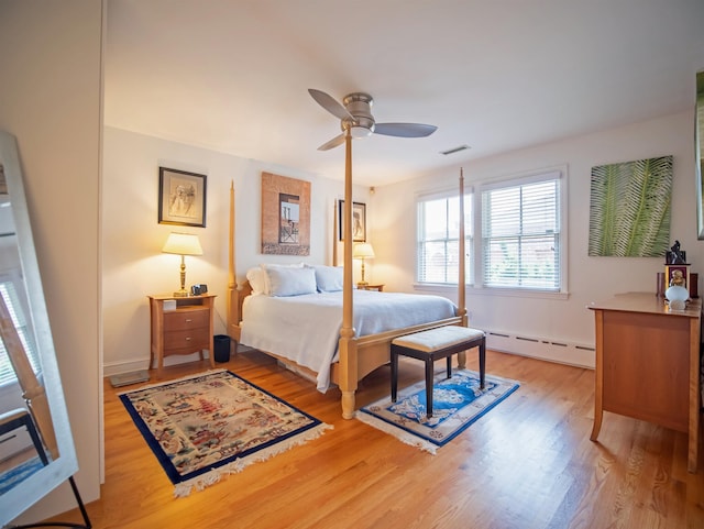 bedroom featuring ceiling fan, light wood-type flooring, and a baseboard heating unit