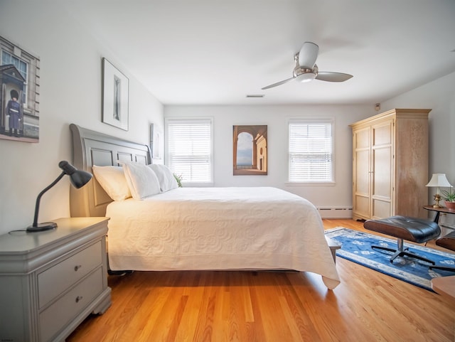 bedroom featuring baseboard heating, light wood-type flooring, and ceiling fan