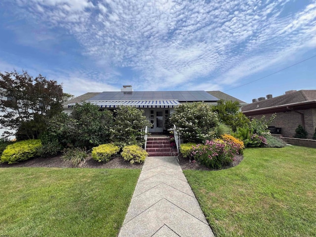 view of front of property with a front yard and solar panels