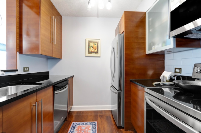 kitchen with tasteful backsplash, appliances with stainless steel finishes, a textured ceiling, dark hardwood / wood-style floors, and sink