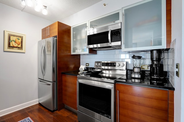 kitchen with dark wood-type flooring, tasteful backsplash, appliances with stainless steel finishes, and a textured ceiling