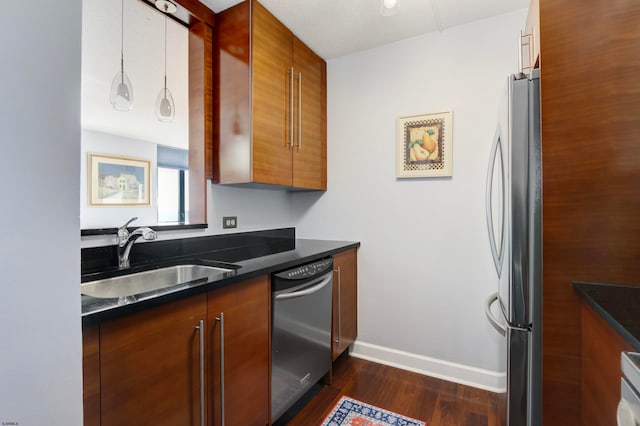 kitchen featuring stainless steel appliances, dark wood-type flooring, a textured ceiling, sink, and decorative light fixtures