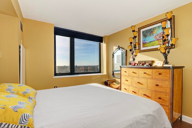 bedroom with multiple windows and dark hardwood / wood-style floors