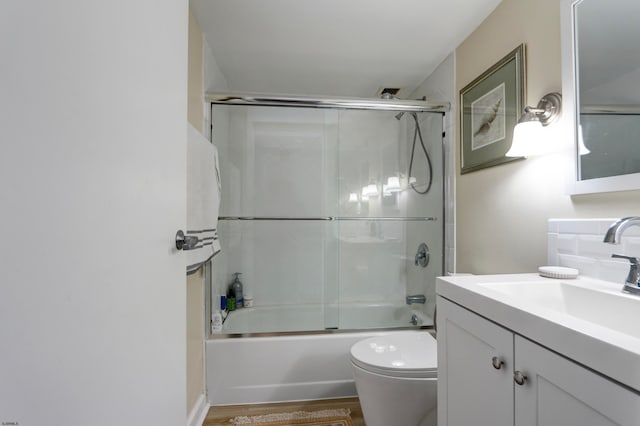 full bathroom featuring shower / bath combination with glass door, hardwood / wood-style flooring, toilet, and vanity