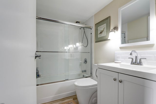 full bathroom featuring enclosed tub / shower combo, hardwood / wood-style floors, vanity, toilet, and decorative backsplash