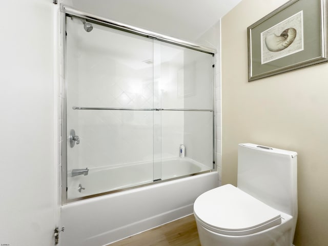 bathroom with toilet, hardwood / wood-style flooring, and enclosed tub / shower combo