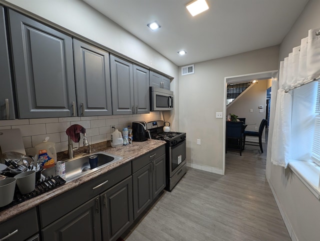 kitchen with tasteful backsplash, stainless steel appliances, and light hardwood / wood-style floors