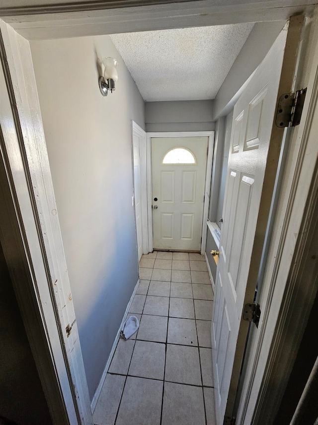 doorway to outside featuring a textured ceiling and light tile patterned flooring