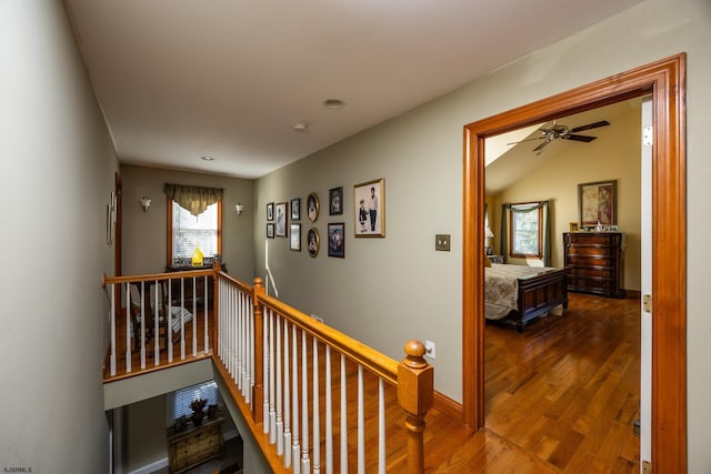 hallway with lofted ceiling and hardwood / wood-style flooring