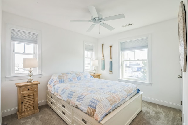 bedroom with multiple windows, dark carpet, and ceiling fan