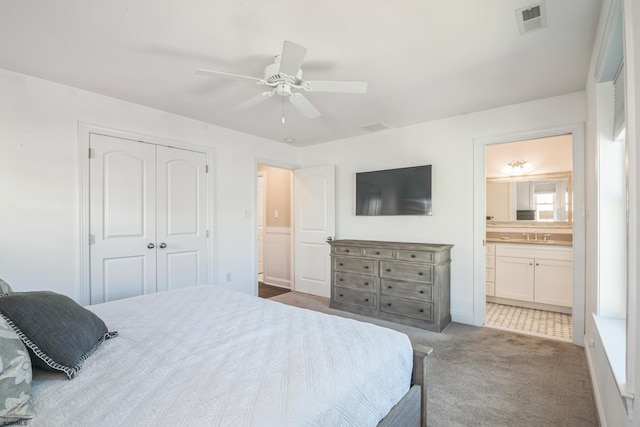 carpeted bedroom with connected bathroom, a closet, sink, and ceiling fan