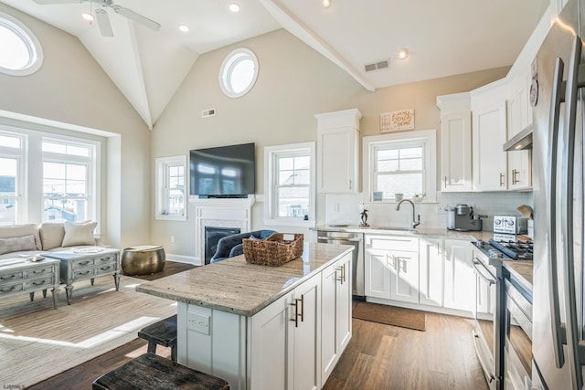 kitchen with stainless steel appliances, wood-type flooring, white cabinetry, and a kitchen island