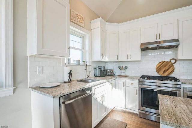 kitchen with white cabinetry, appliances with stainless steel finishes, sink, and light stone countertops