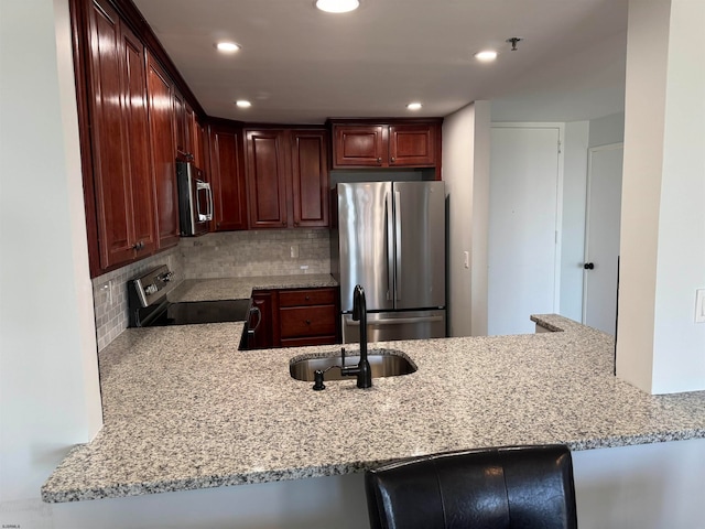 kitchen featuring kitchen peninsula, stainless steel appliances, decorative backsplash, and light stone counters