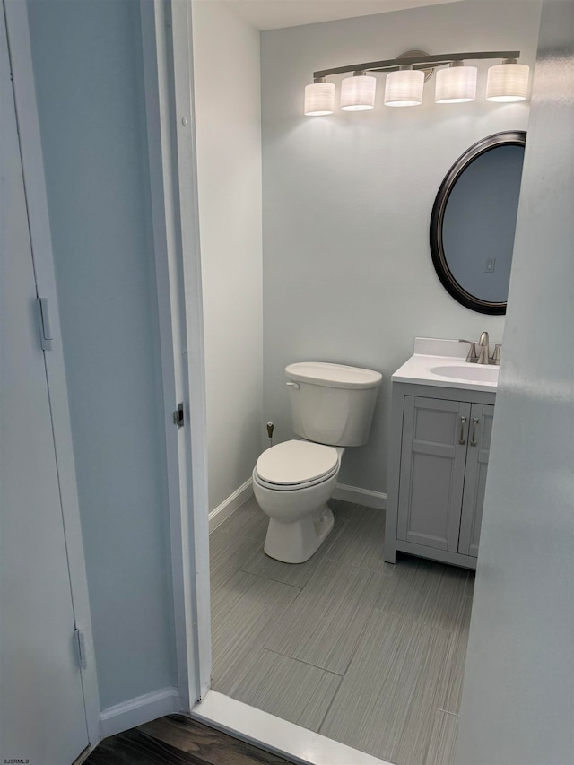 bathroom with toilet, vanity, and wood-type flooring