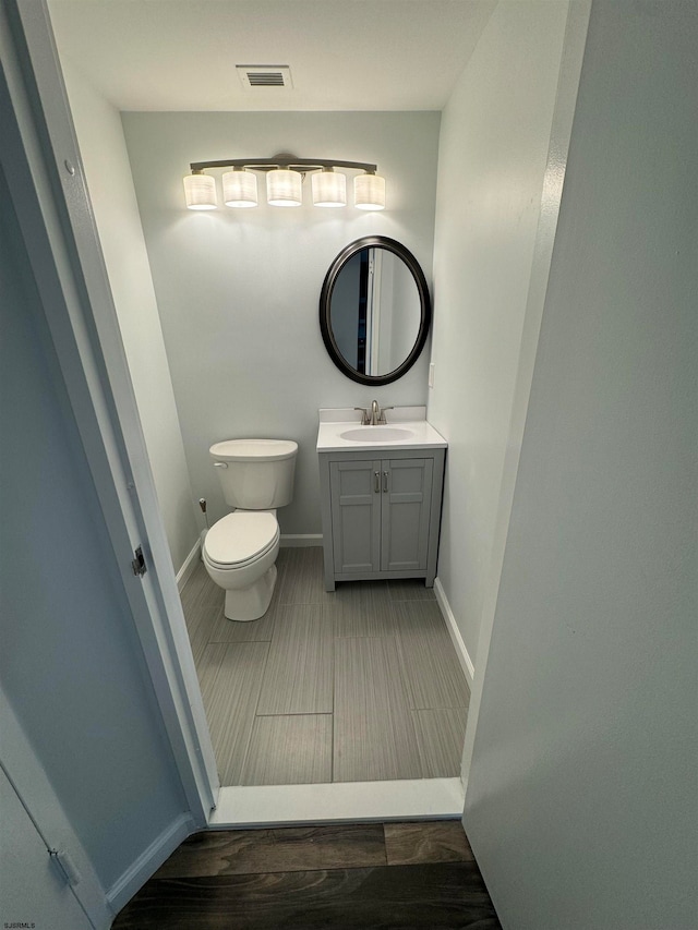 bathroom with wood-type flooring, vanity, and toilet