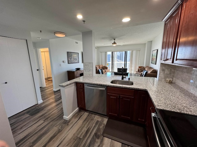 kitchen with dark wood-type flooring, kitchen peninsula, decorative backsplash, sink, and appliances with stainless steel finishes