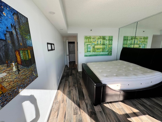 bedroom featuring dark hardwood / wood-style flooring, a closet, and a textured ceiling