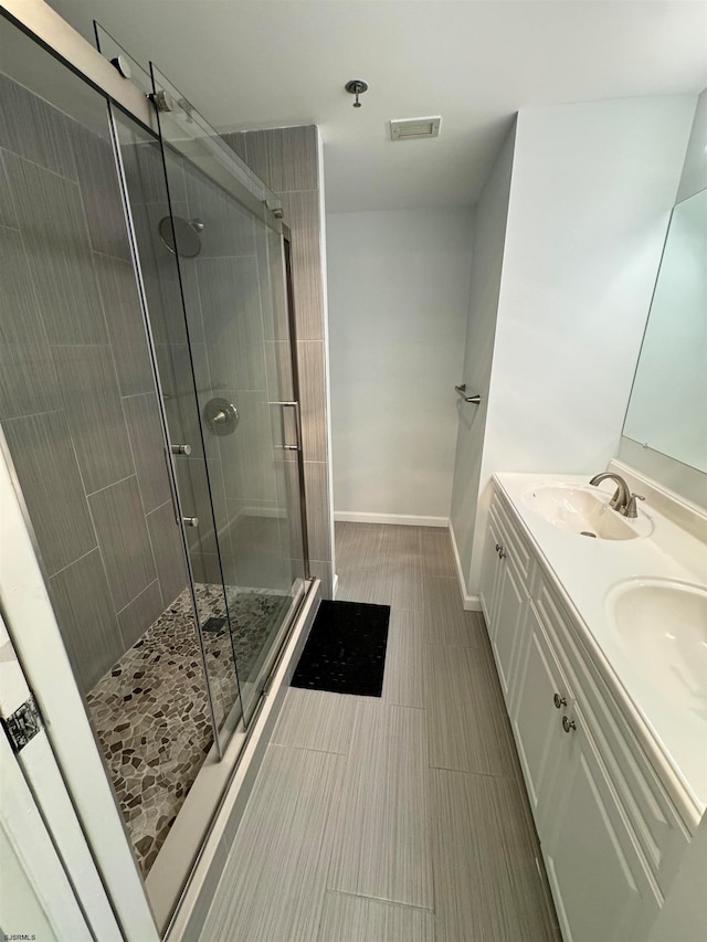 bathroom with a shower with shower door and vanity