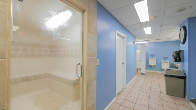 bathroom with a drop ceiling, tile patterned floors, and a shower with shower door