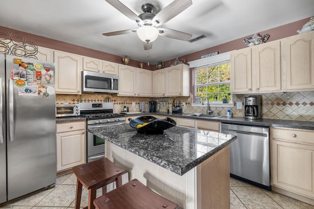 kitchen featuring stainless steel appliances, sink, a kitchen bar, backsplash, and a center island