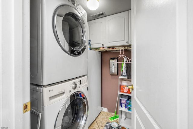 washroom featuring stacked washer / dryer, cabinets, and tile patterned floors