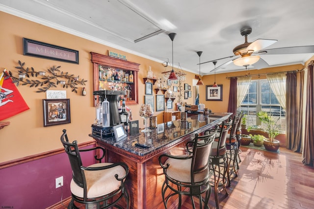 bar with pendant lighting, hardwood / wood-style floors, ceiling fan, and crown molding